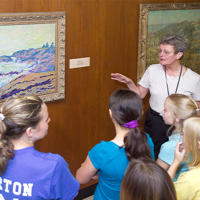 volunteer docent explaining artwork to young kids